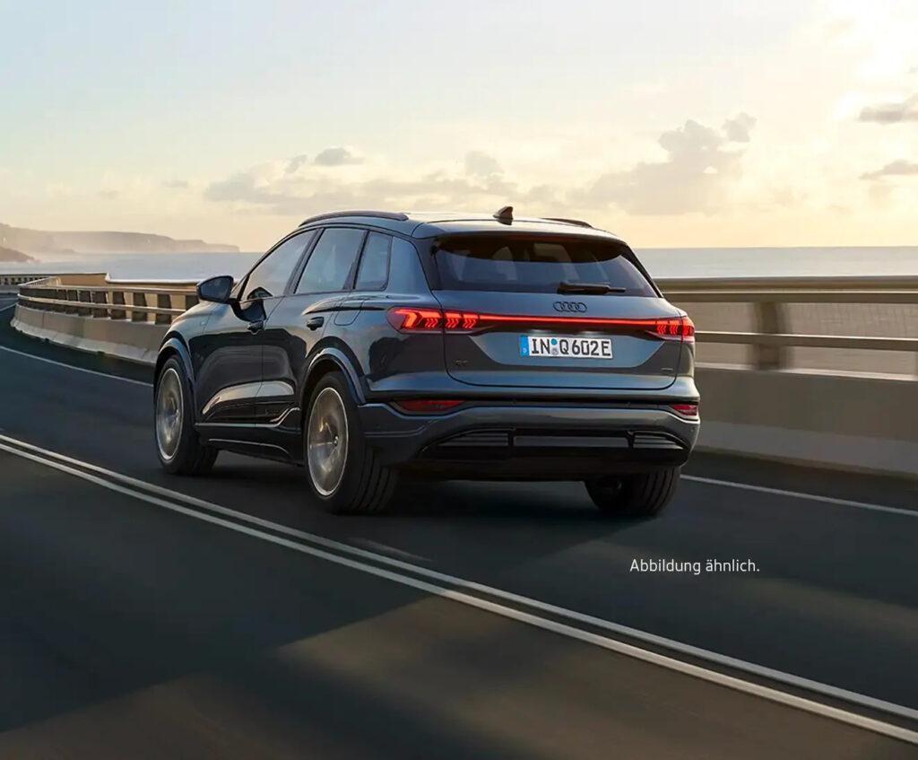 Audi Q6 e-tron Elektro-SUV fährt auf Küstenstraße bei Sonnenuntergang
