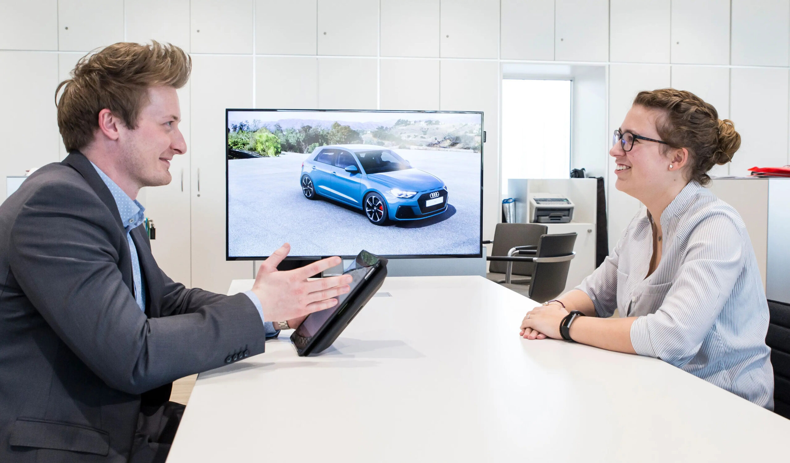 Verkäufer und Kundin sitzen an einem Beratungstisch im Autohaus Hans Maier Erding