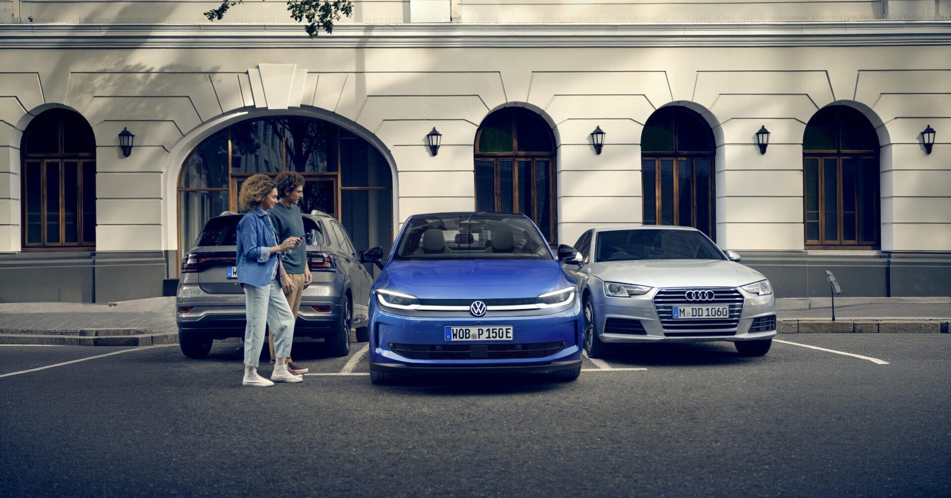 Blauer ID. Polo steht zwischen zwei anderen parkenden Autos. Davor geht ein Pärchen auf der Straße vorbei.
