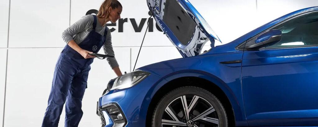 Mechatronikerin schaut in den Motorraum von Volkswagen