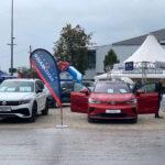 Drei Volkswagen-Modelle auf der Autoschau Erding 2022, darunter ein weißer Tiguan und ein roter ID.4 GTX mit geöffneten Türen, im Hintergrund Zelte und Besucher.