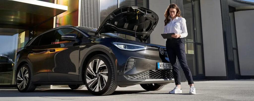 Frau führt Fahrzeug-Check an einem Volkswagen durch