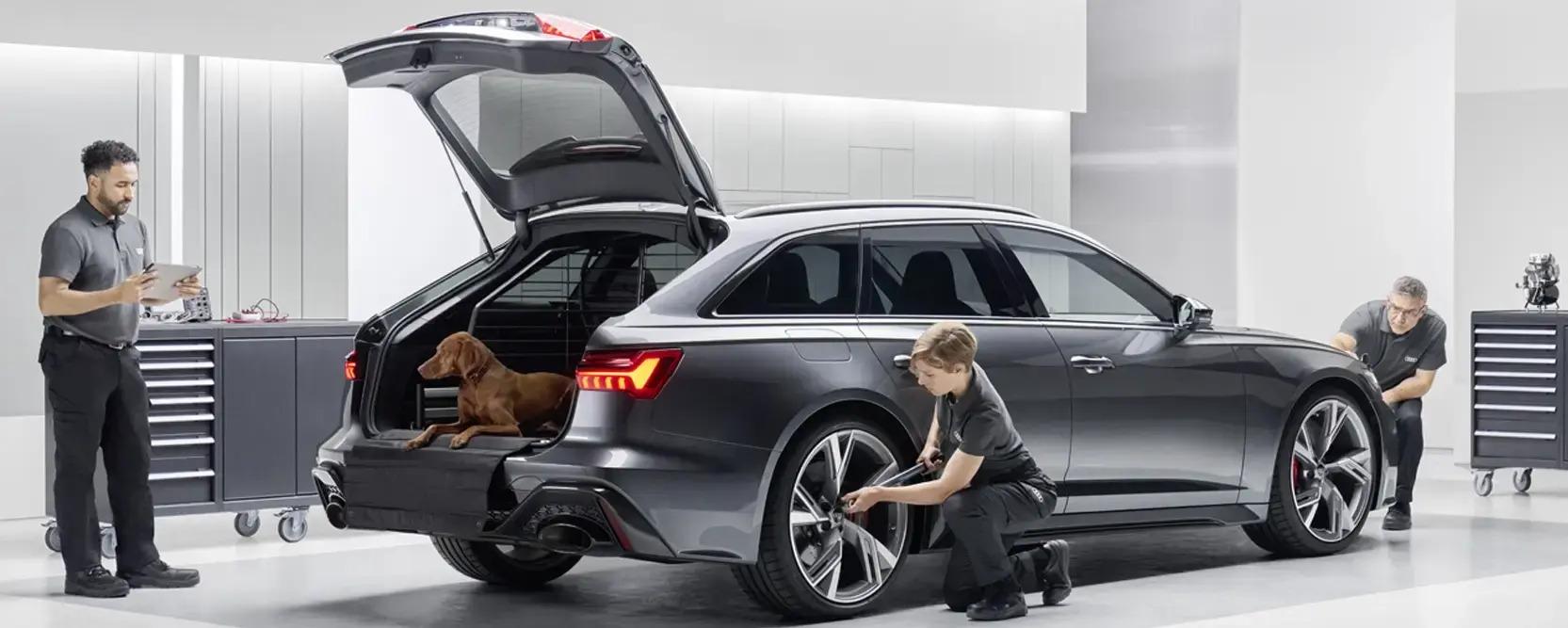 Werkstattmitarbeiter prüfen Audi mit geöffneter Heckklappe