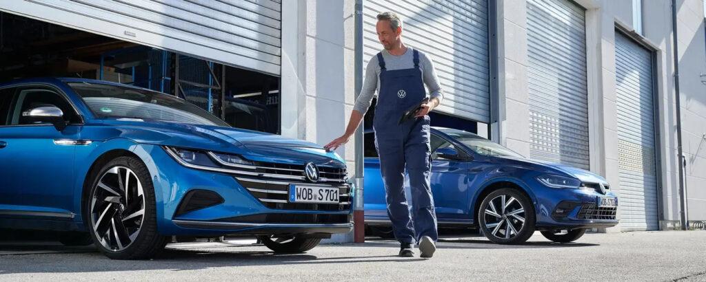 Servicemitarbeiter prüft Volkswagen Modelle vor Rolltor