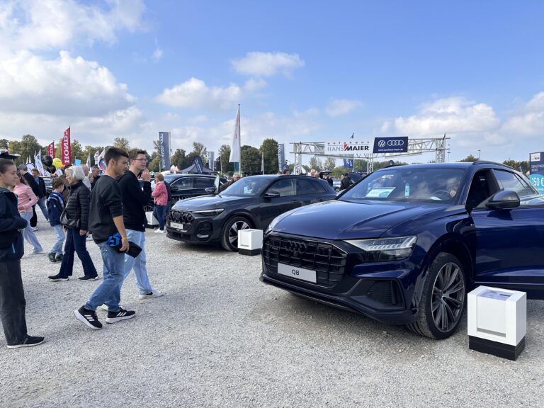 Großes Interesse an der Automobil Ausstellung Erding 2025 3 Ein dunkelblauer Audi Q8 und ein schwarzer Audi Q5 auf einem Schotterplatz bei der Automobilausstellung Erding 2025, umgeben von Besuchern und Werbebannern.