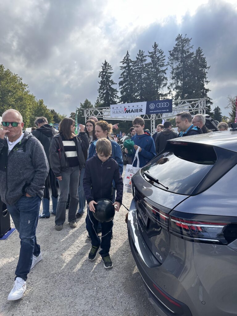 Großes Interesse an der Automobil Ausstellung Erding 2025 24 Menschenmenge auf der Automobilausstellung Erding 2025 am Audi und VW Stand mit Banner 'Autohaus Hans Maier', im Vordergrund graues Auto mit Heckansicht.