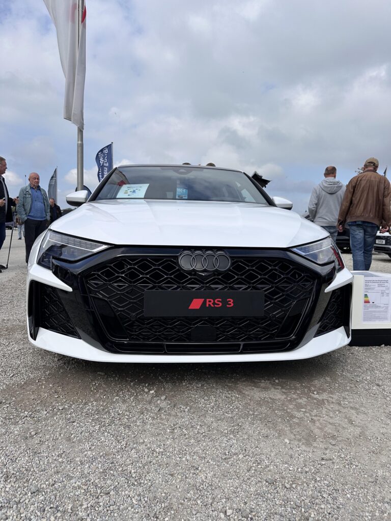 Großes Interesse an der Automobil Ausstellung Erding 2025 21 Weiße Audi RS 3 Limousine mit schwarzem Wabengrill und vier Ringen, Frontansicht auf der Automobilausstellung Erding 2025.