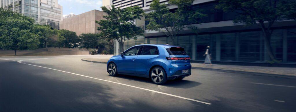 der neue vw id polo in blau fährt auf einer Straße entlang, die gesäumt ist von Bäumen