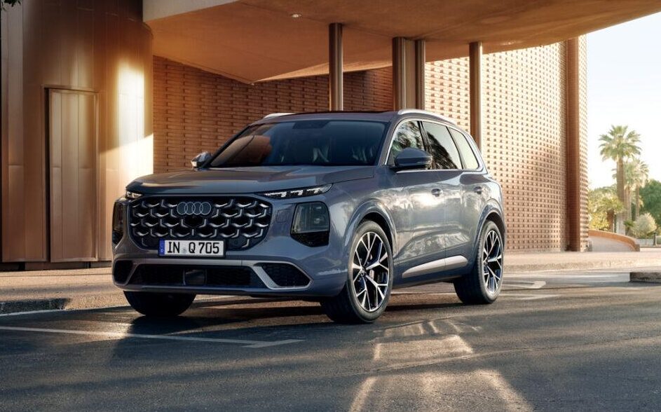 Audi Q7 SUV mit markantem Wabengrill, großen Felgen und moderner LED-Beleuchtung vor einem Gebäude mit Säulen und Ziegelmauerwerk