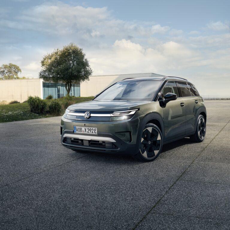 ID. Cross Privatleasing 3 Der neue VW ID. Cross in der Farbe Nori Green Metallic steht auf einem geteerten Platz mit eingeschalteten Scheinwerfern.
