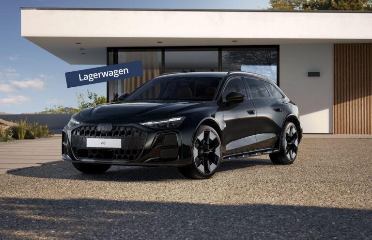 Mitternachtsgrüner Audi A6 allroad als Lagerwagen vor modernem Gebäude auf Kiesfläche
